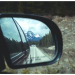 tilt shift photography of side mirror reflecting snow capped mountain